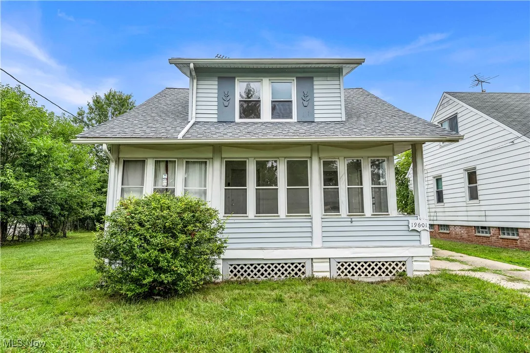 View of home's exterior featuring a shingled roof, a yard, and a sunroom