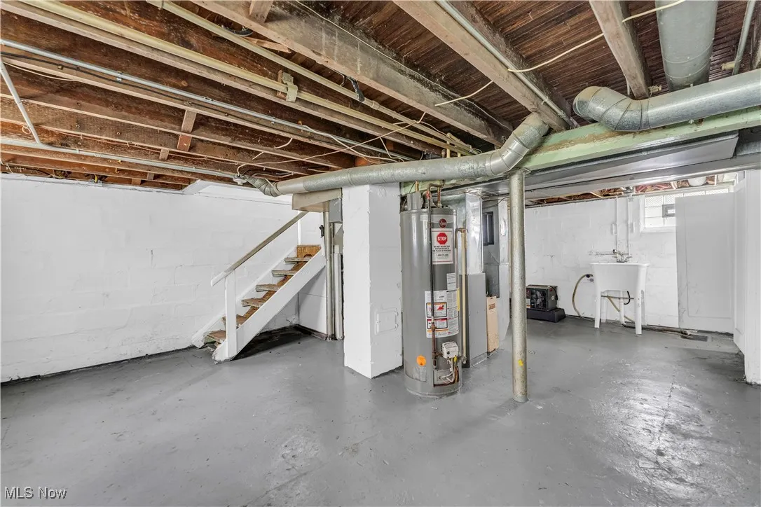 Basement with stairs, gas water heater, and heating unit