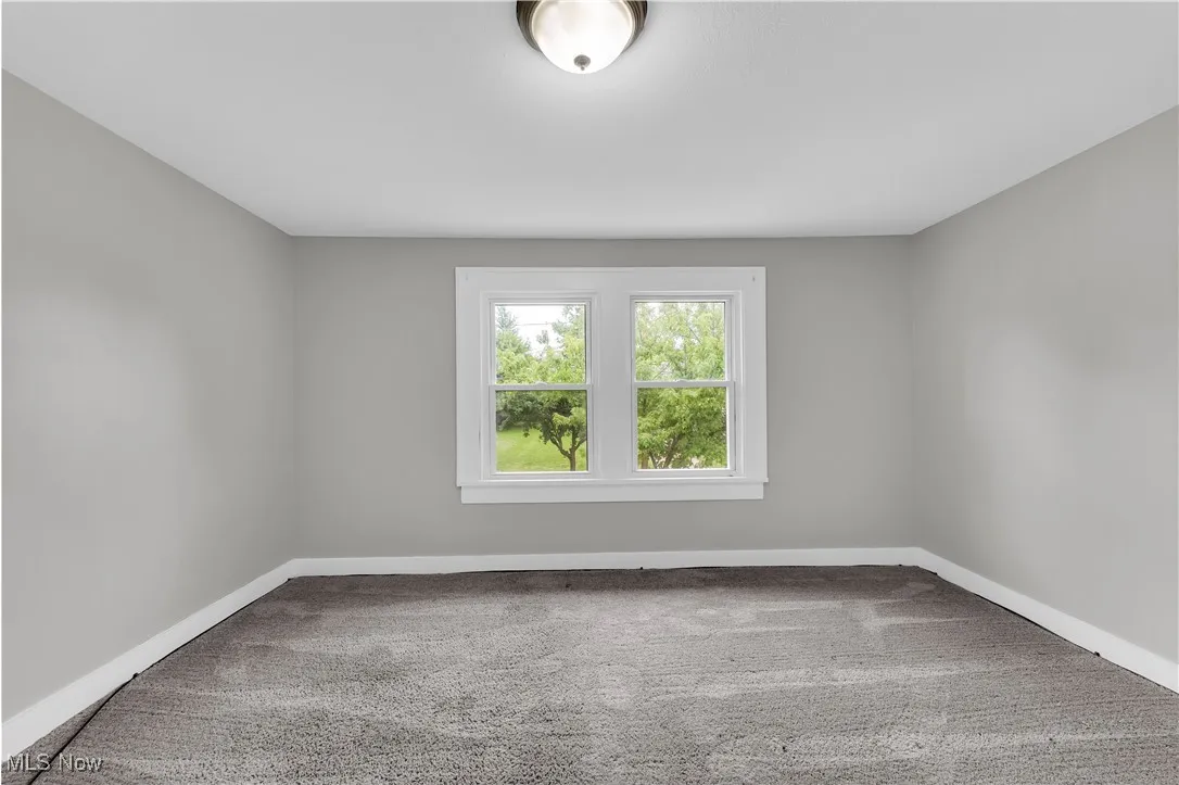 Empty room featuring light colored carpet and baseboards