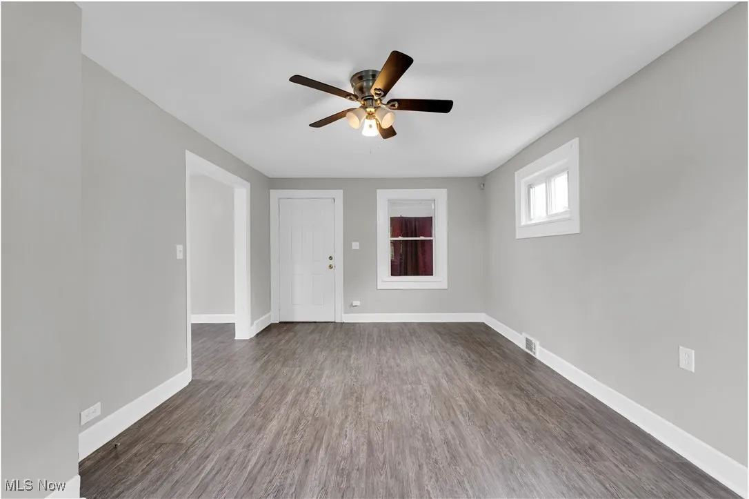 Empty room featuring dark wood finished floors and a ceiling fan