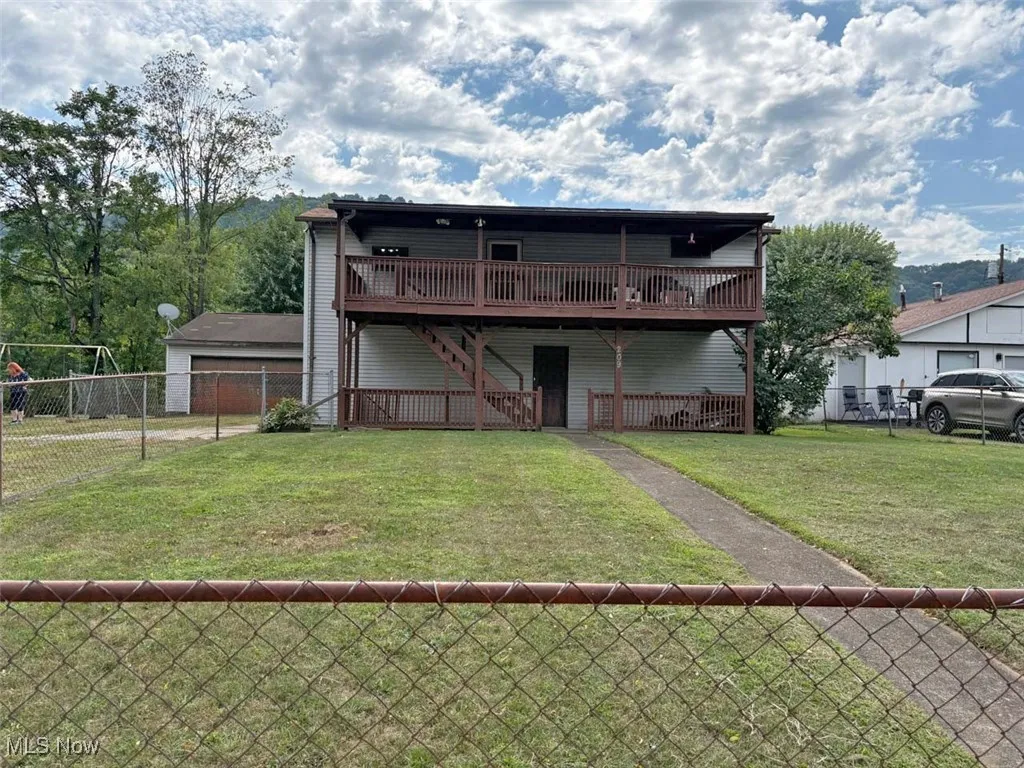 Front
 view of property with a deck, a fenced backyard, and stairway