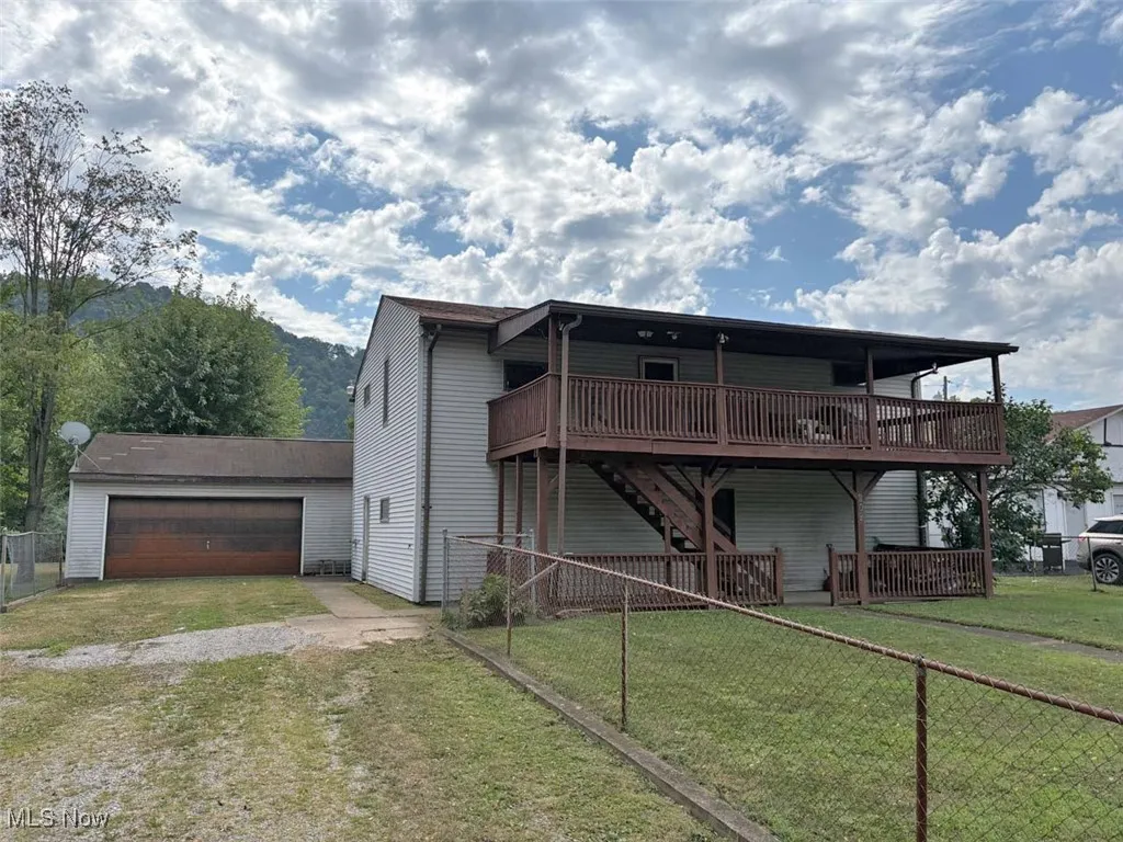 Front of property featuring a deck, stairs, driveway, and a garage