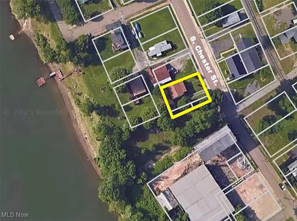 Aerial perspective of suburban area with a large body of water and property parcel outlined