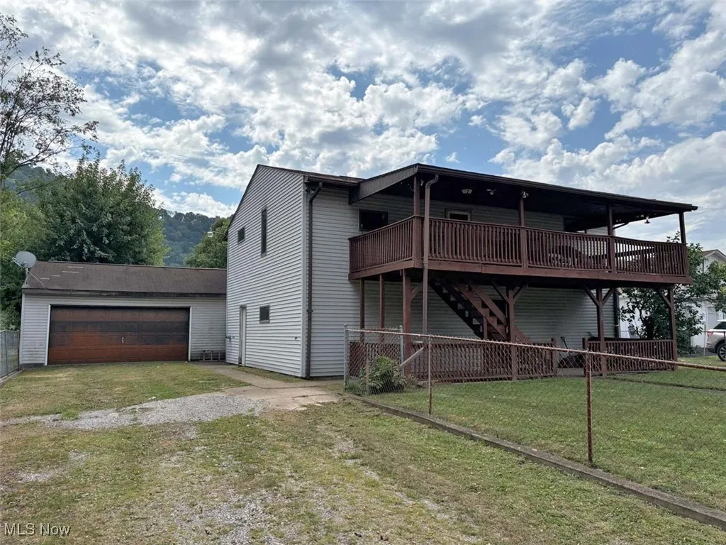 Front of house with a wooden deck, a garage, stairs, and driveway