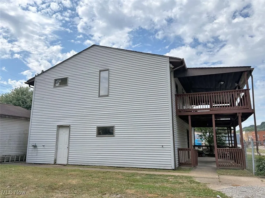 Side view of house with stairs and a yard