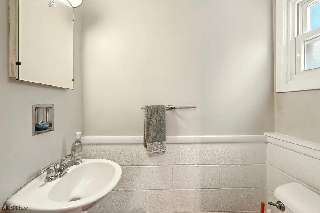 Lower level half bathroom featuring toilet and a sink