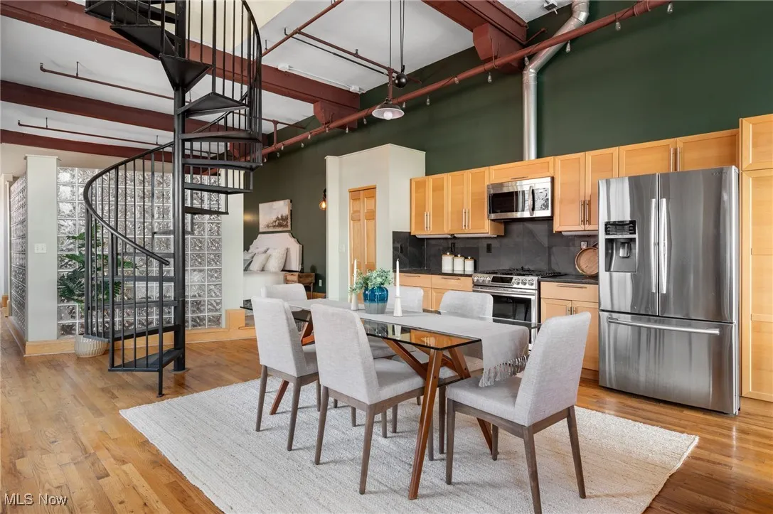 Dining area with stairway, light wood-style flooring, and a towering ceiling