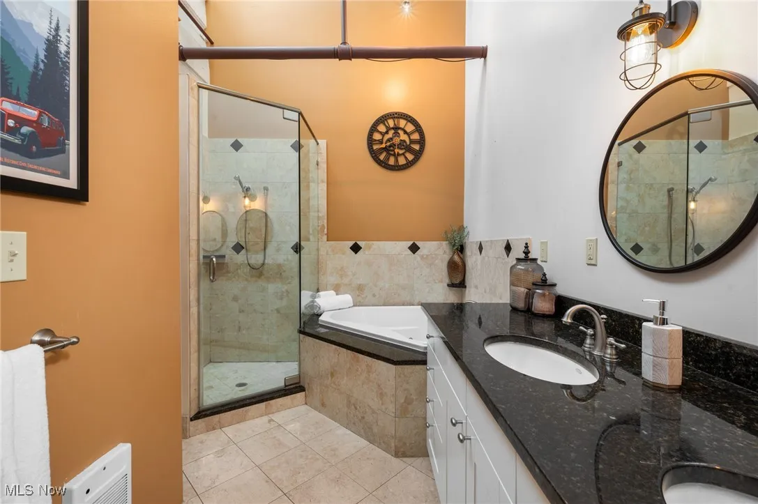 Bathroom with a stall shower, a garden tub, double vanity, and light tile patterned flooring