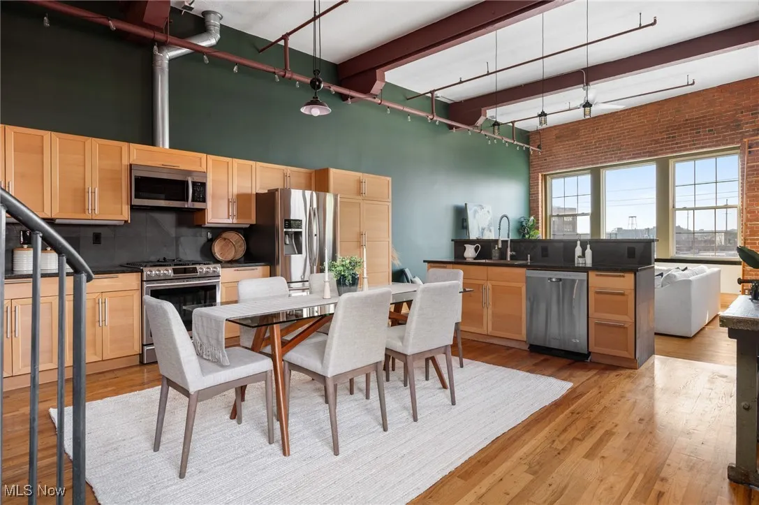 Dining space featuring light wood-style flooring, brick wall, and a high ceiling