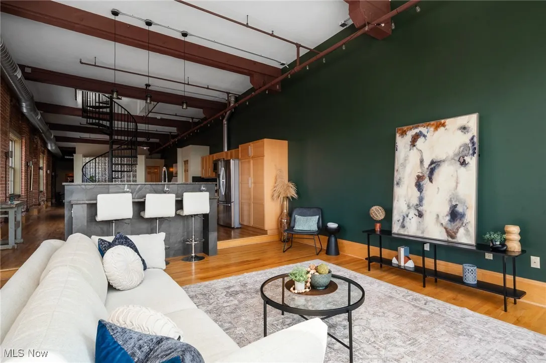 Living room featuring wood finished floors, a high ceiling, and stairs