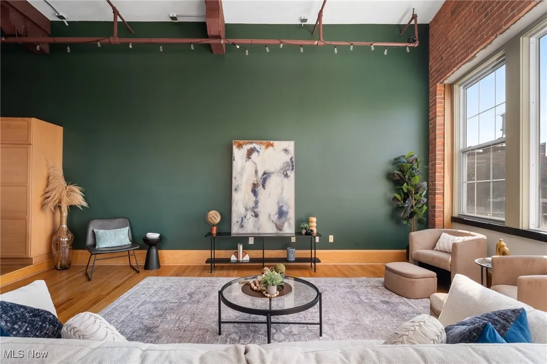 Living area featuring wood finished floors, brick wall, and a towering ceiling