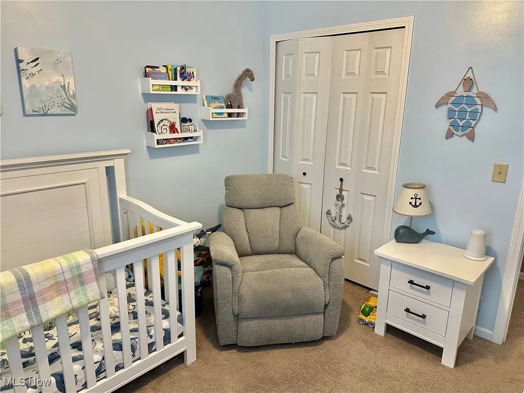 Bedroom with light colored carpet, a nursery area, and a closet