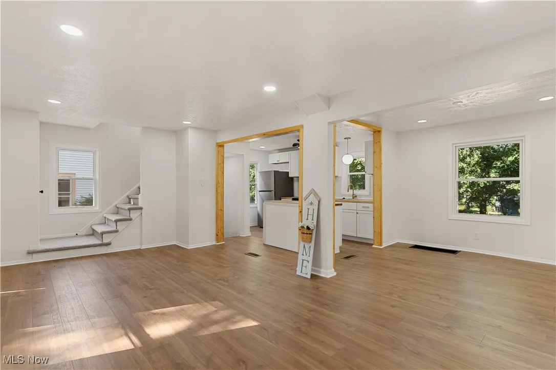 Unfurnished living room featuring recessed lighting, light wood-style floors, and stairway