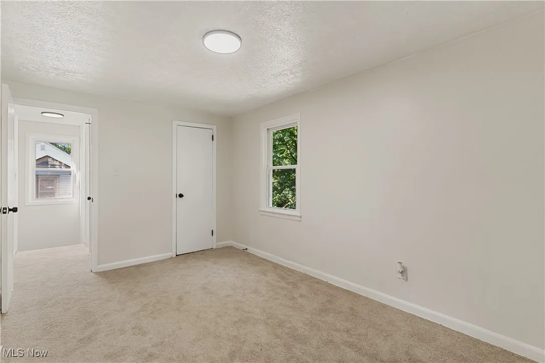 Unfurnished bedroom with light colored carpet and a textured ceiling