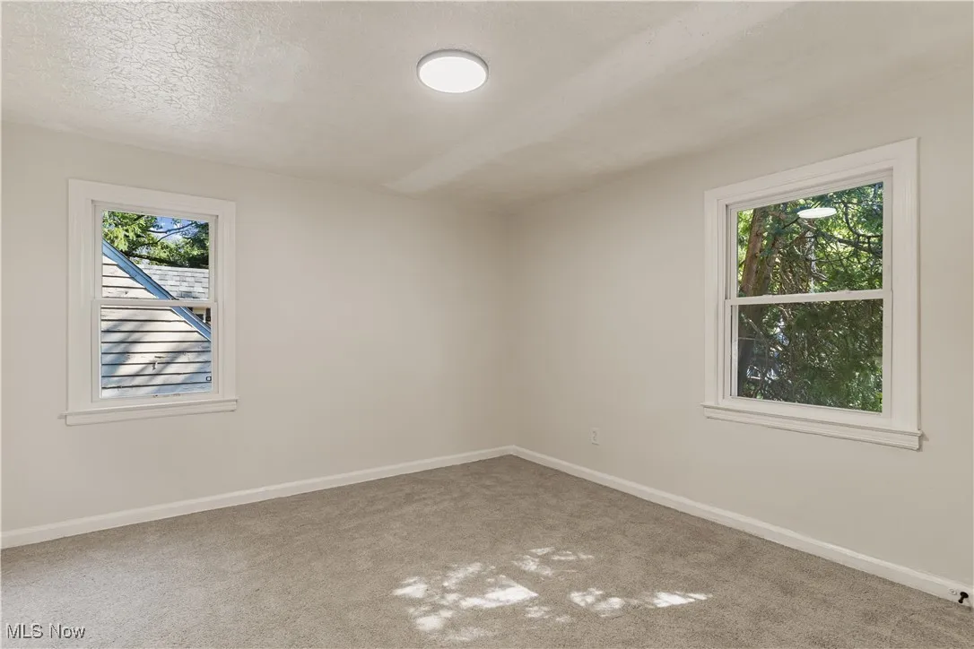 Carpeted empty room with baseboards and a textured ceiling