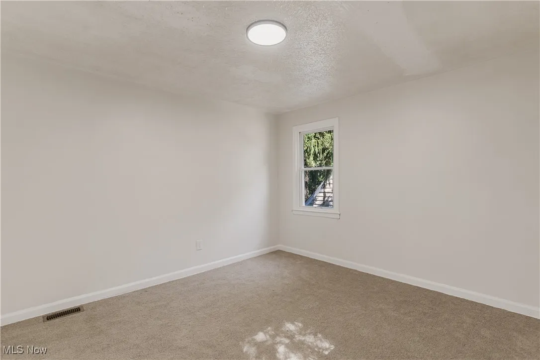 Spare room featuring a textured ceiling and carpet floors