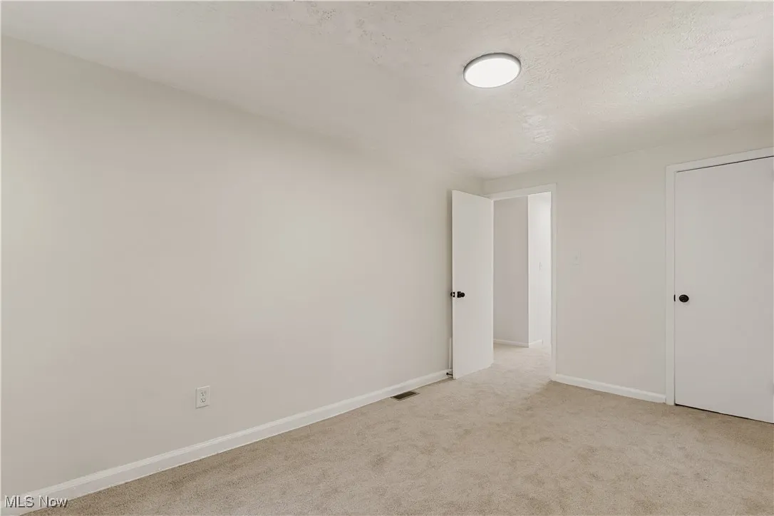 Unfurnished bedroom with a textured ceiling and light carpet