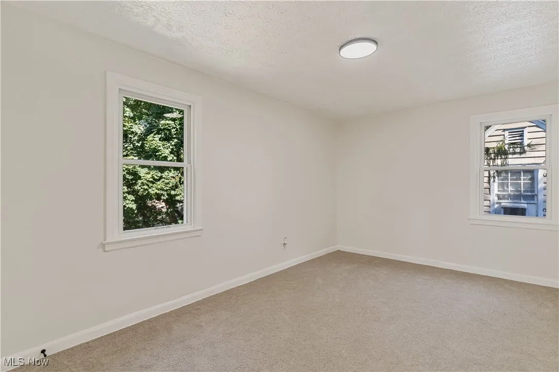 Empty room featuring light colored carpet and a textured ceiling