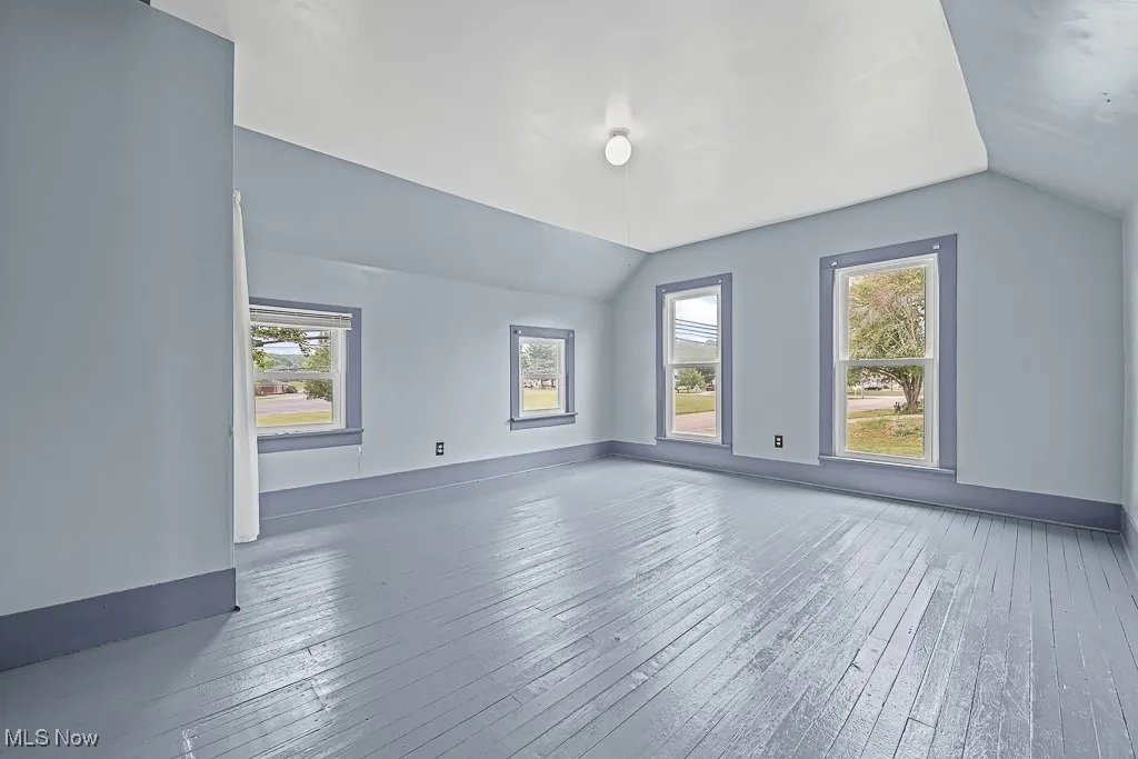 Bedroom with lofted ceiling, healthy amount of natural light, and wood-type flooring