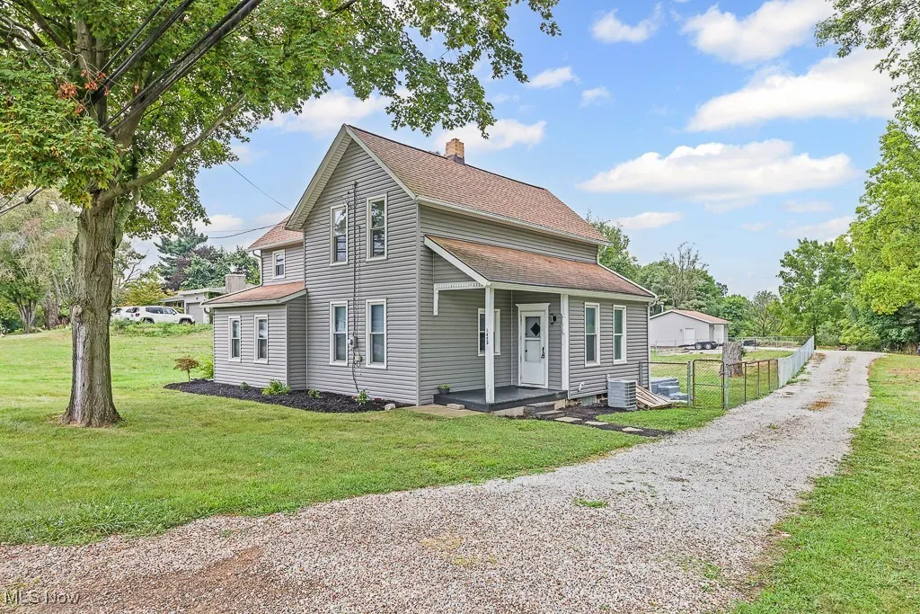 Traditional home with a shingled roof, a chimney, a front yard, and driveway