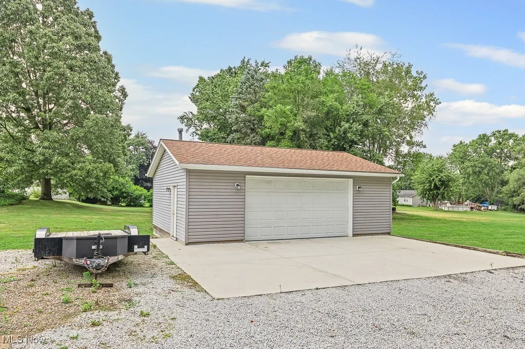 Detached garage featuring view of scattered trees