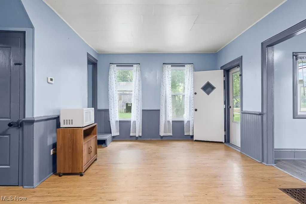 Entryway with light wood-style floors, healthy amount of natural light, and wainscoting