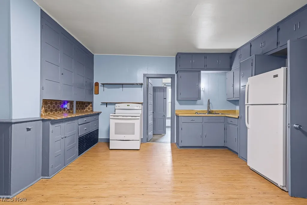 Kitchen with white appliances, light wood finished floors, tasteful backsplash, and gray cabinetry