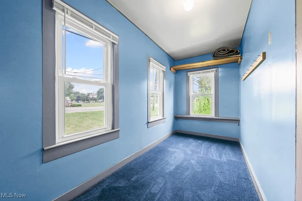 Empty closet in primary bedroom featuring dark carpet and baseboards