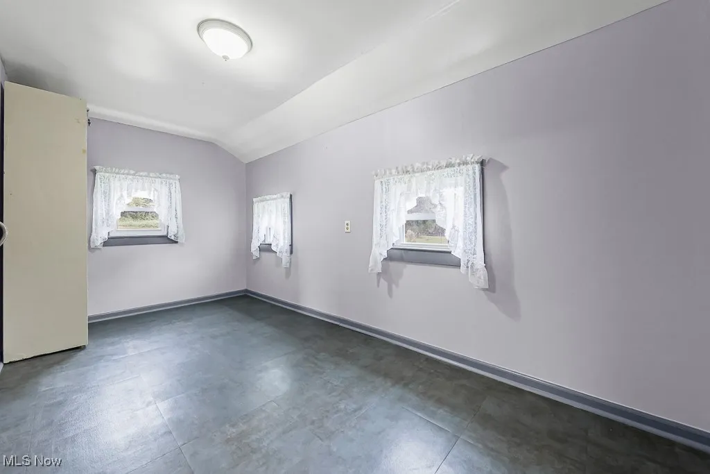 Laundry room featuring lofted ceiling and baseboards