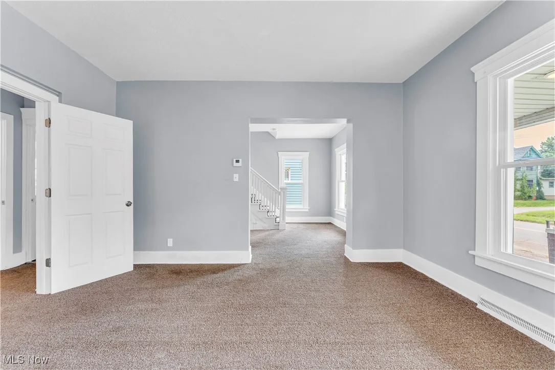 Empty room featuring light carpet and stairway