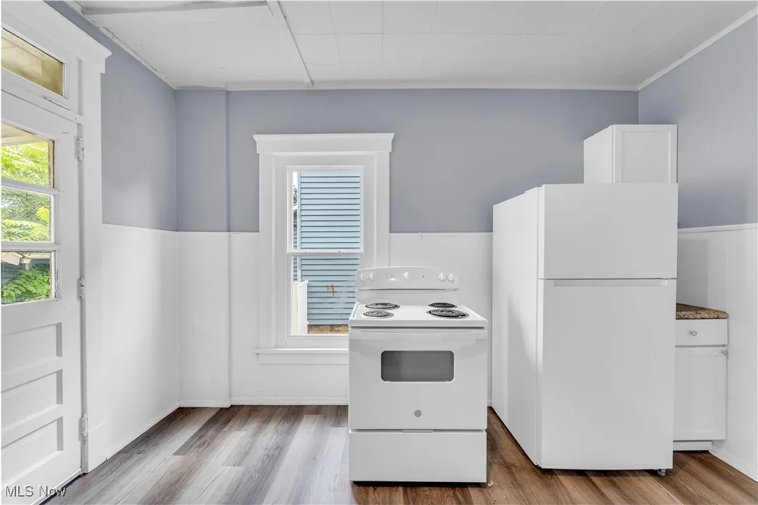 Kitchen featuring white appliances, light wood-type flooring, and white cabinets