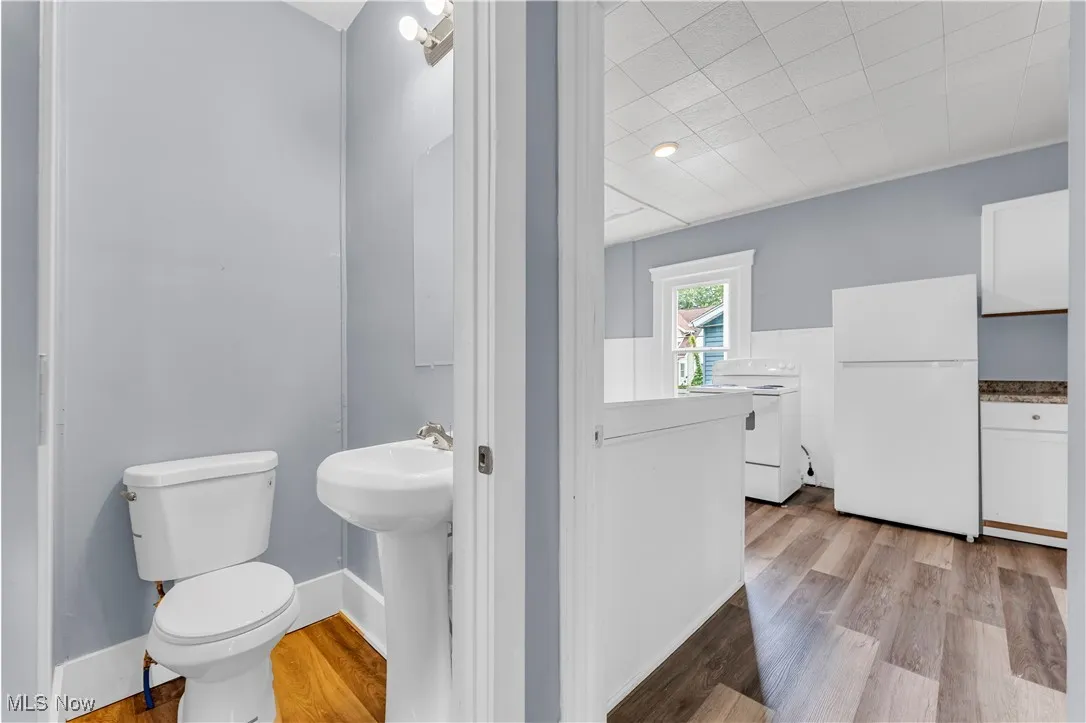 Half bath with light wood-type flooring and toilet