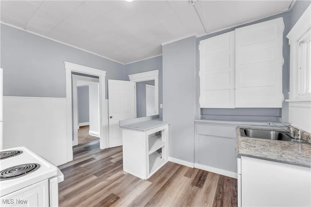 Kitchen with white cabinets, white electric range oven, light wood-style floors, crown molding, and open shelves