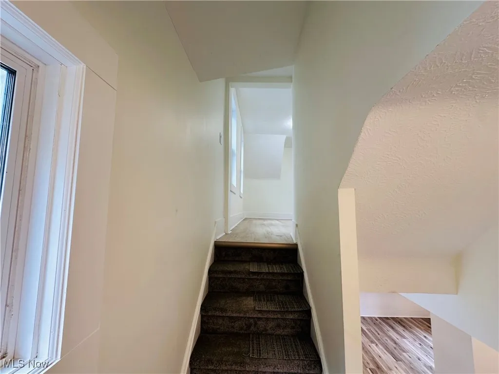 Staircase featuring wood finished floors and vaulted ceiling