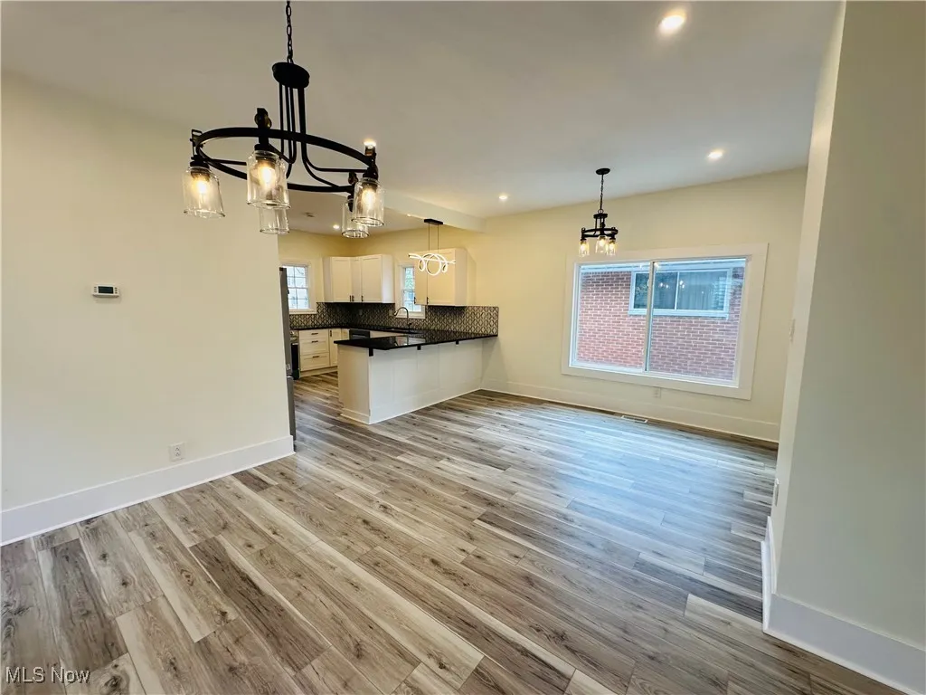 Kitchen featuring dark countertops, a peninsula, backsplash, hanging light fixtures, and a chandelier