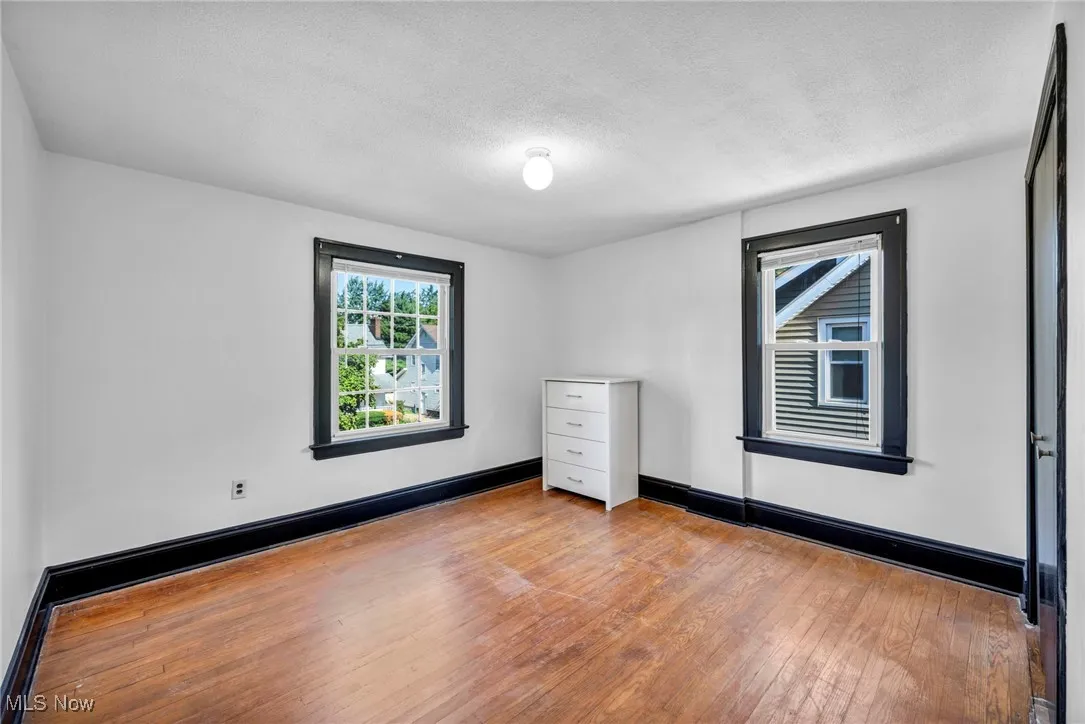 Empty room with hardwood / wood-style flooring and a textured ceiling