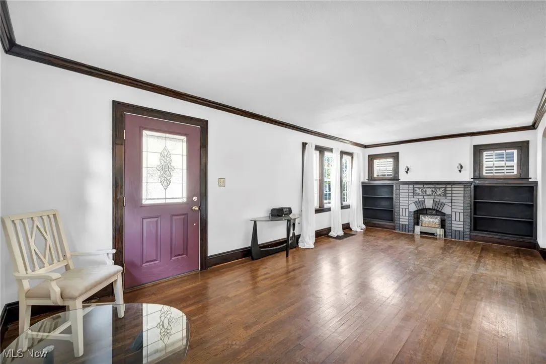 Entryway featuring ornamental molding, dark wood finished floors, and a fireplace