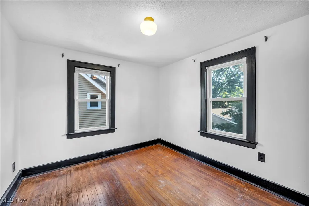 Empty room with hardwood / wood-style floors and a textured ceiling