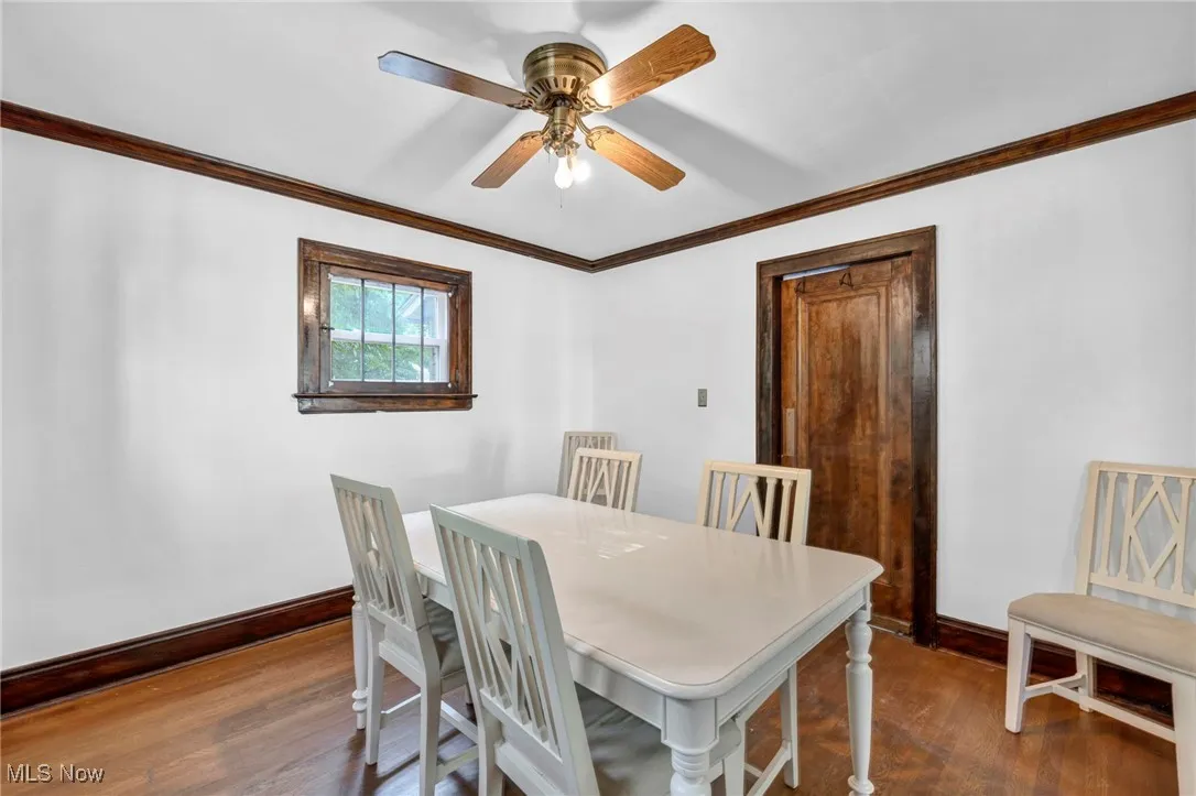 Dining room with crown molding, dark wood-style floors, and ceiling fan