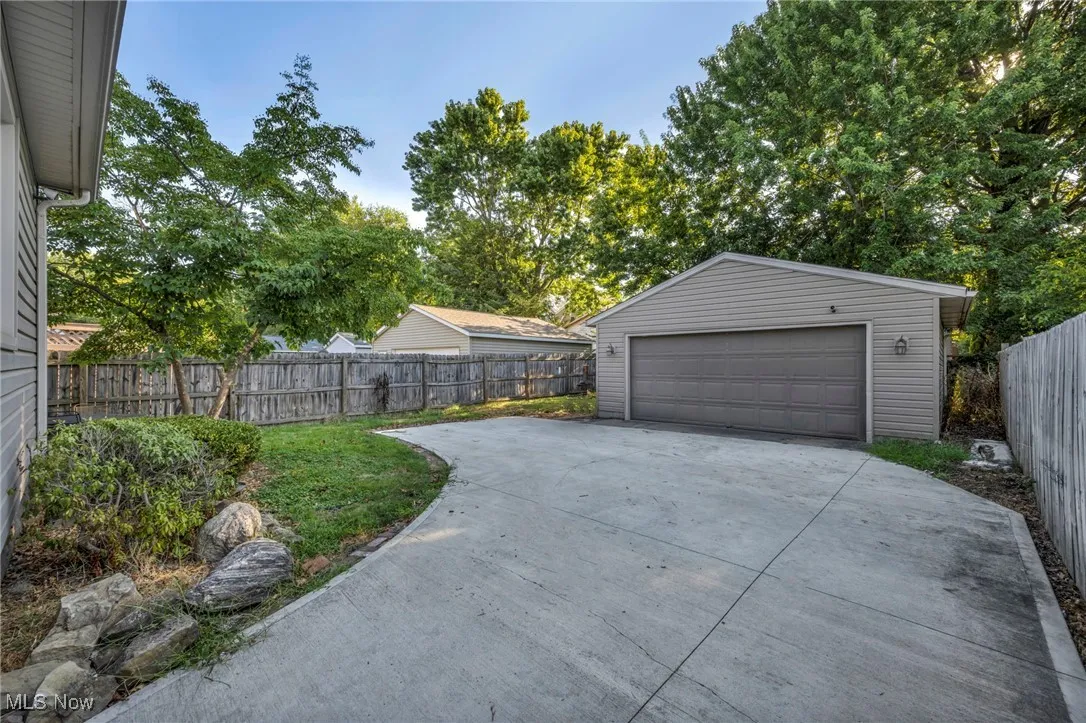 Detached garage featuring view of scattered trees