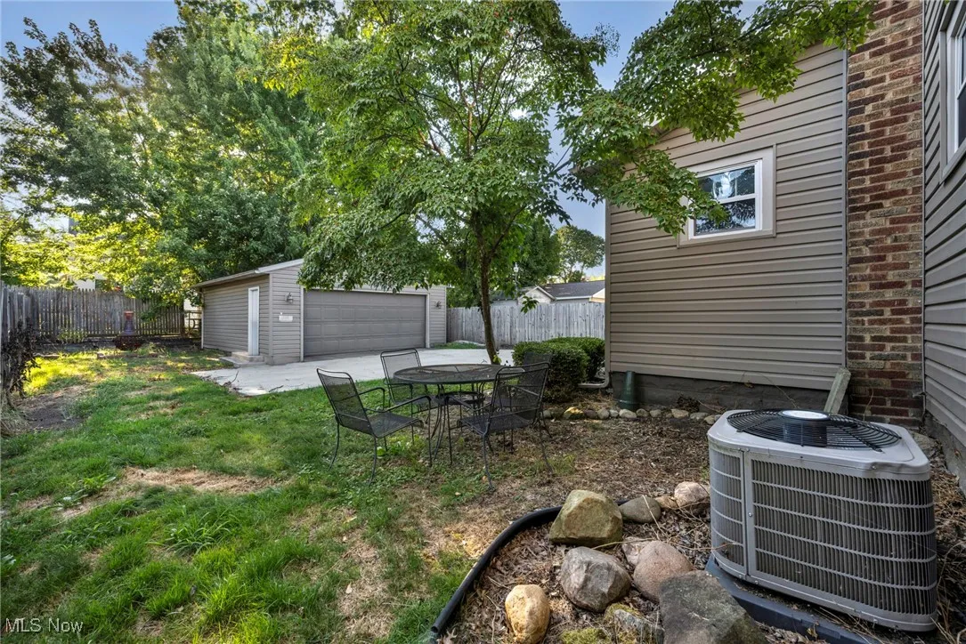Fenced backyard featuring an outdoor structure, a garage, and a patio