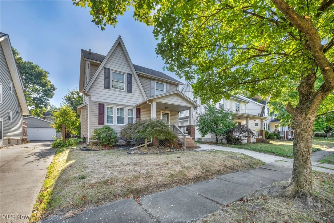 View of front of property featuring a porch, an outdoor structure, a garage, and a front lawn