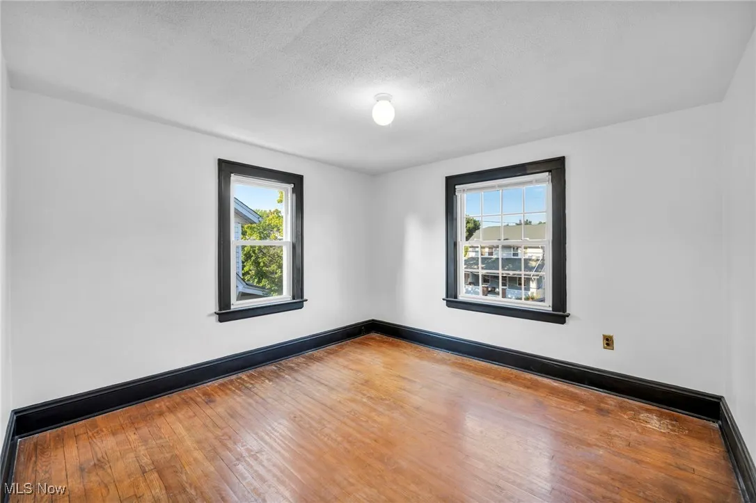 Spare room featuring healthy amount of natural light, hardwood / wood-style floors, a textured ceiling, and baseboard heating
