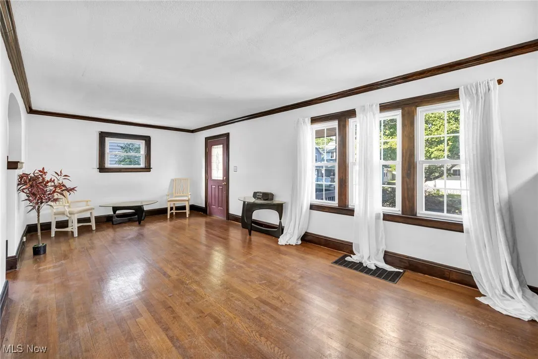 Living area featuring crown molding and dark wood-type flooring