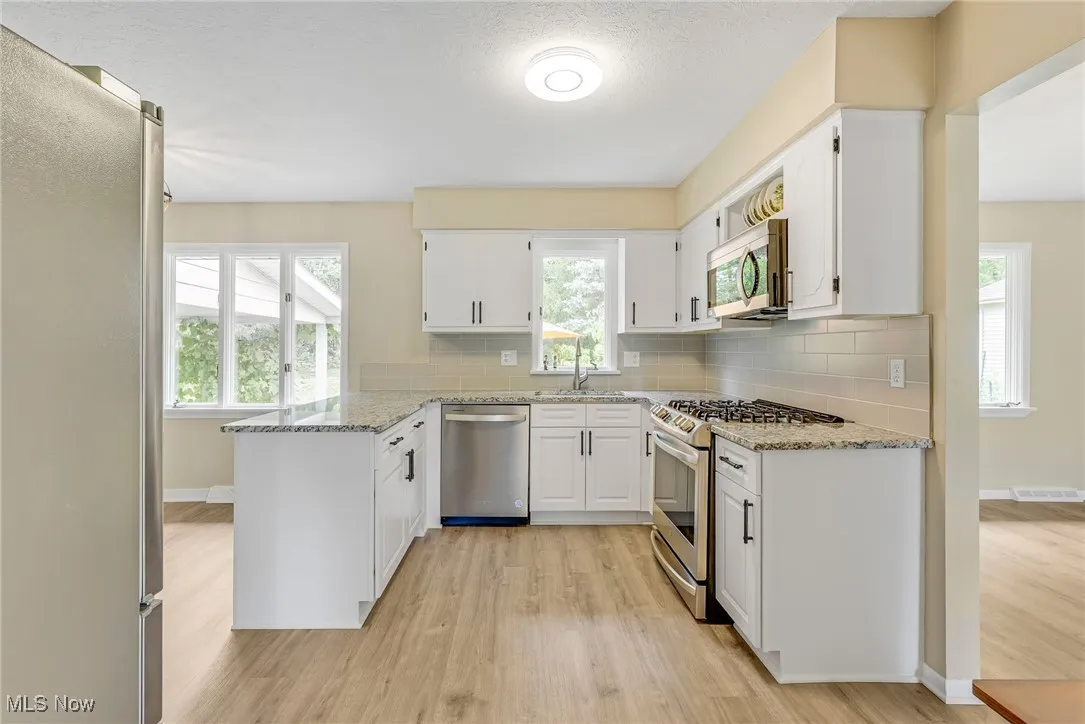 Updated eat-in kitchen has granite counters, tiled backsplash and newer stainless steel appliances