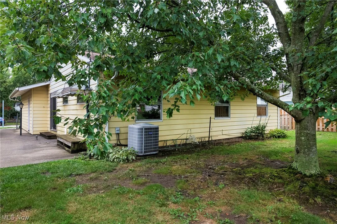 View of side of home featuring a central AC unit and a lawn