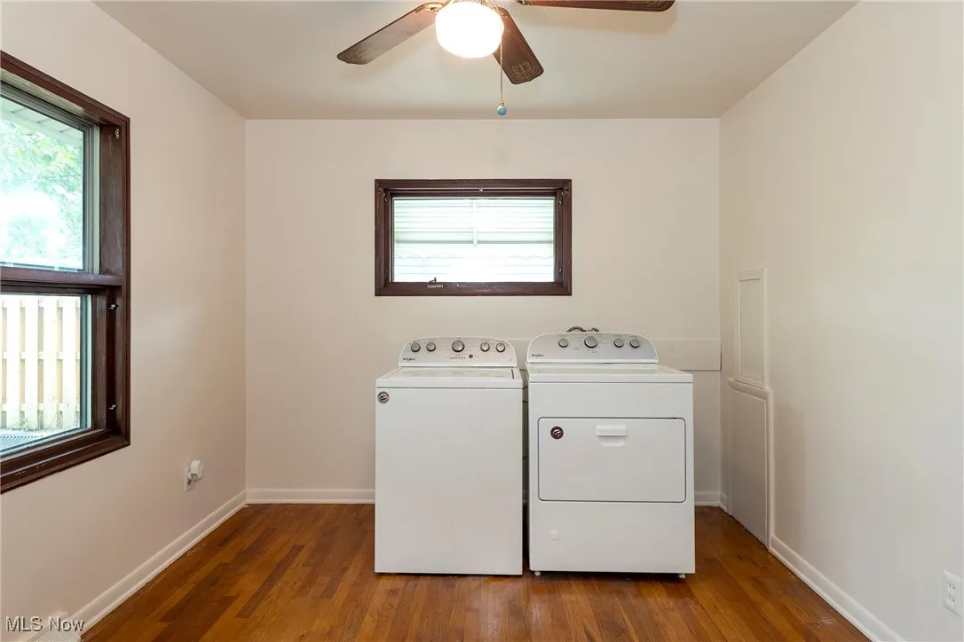 Laundry area with hardwood floors, washer and clothes dryer, and a ceiling fan - can be converted back to a bedroom