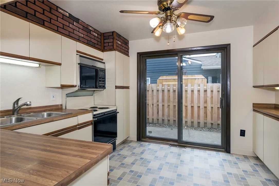 Kitchen featuring microwave, white cabinets, a ceiling fan, range with electric cooktop, light floors and slider to patio