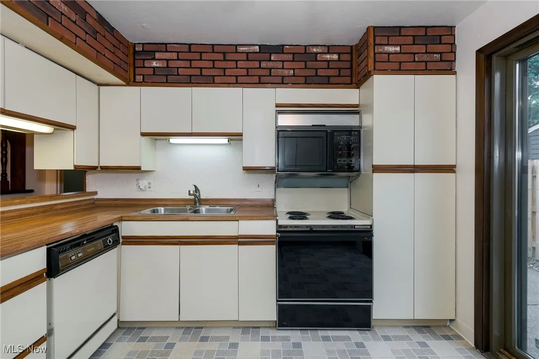 Kitchen with white cabinetry, white dishwasher, and range with electric stovetop