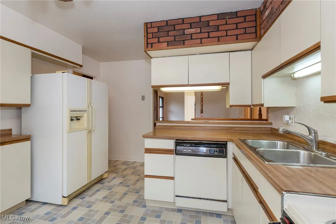 Kitchen with white appliances, white cabinets, countertops, and light flooring
